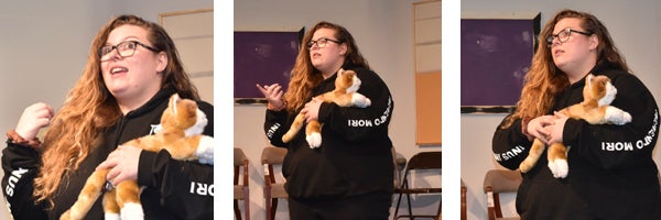 Woman holding a stuffed cat on a stage