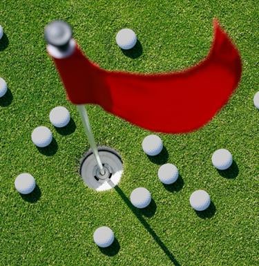 Golf balls scatterd on the green around a golf hole and flag.