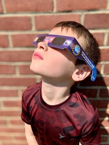 Young boy using eclipse glasses