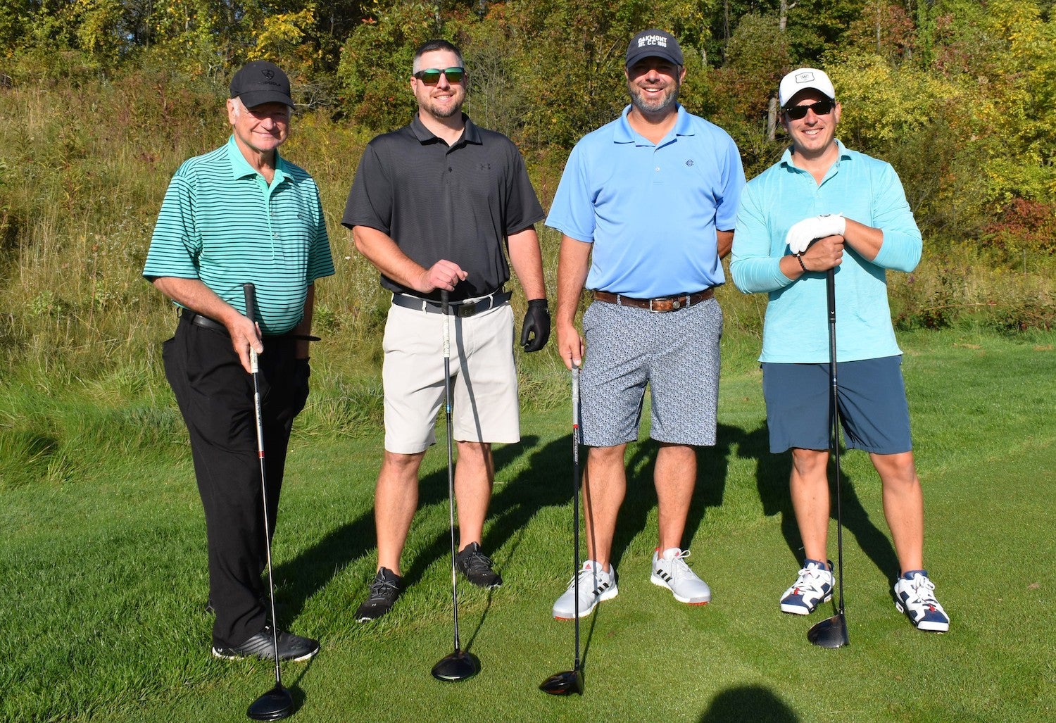 Four individuals posing with golf clubs