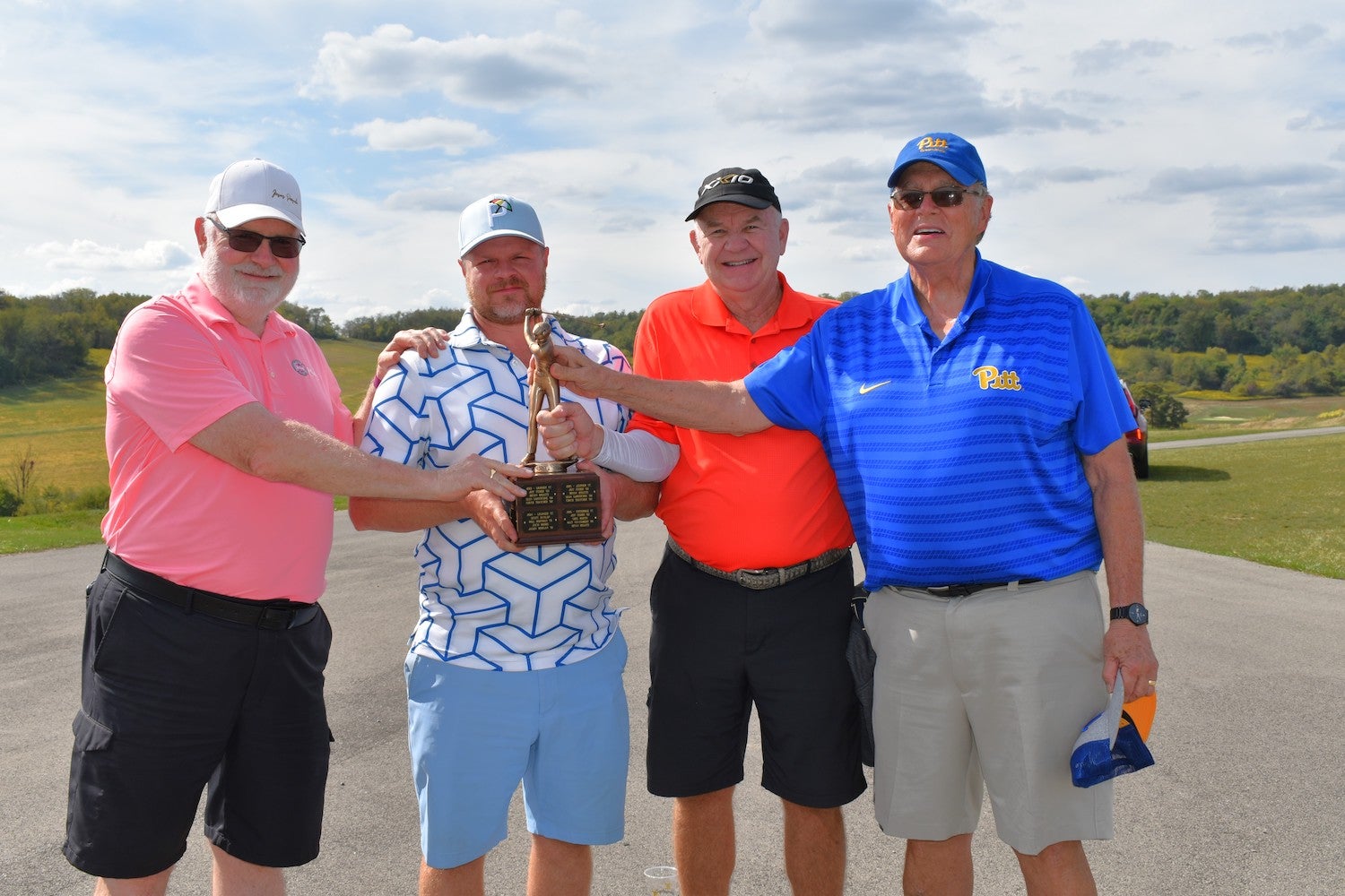 Four individuals posing with Golf Outing trophy