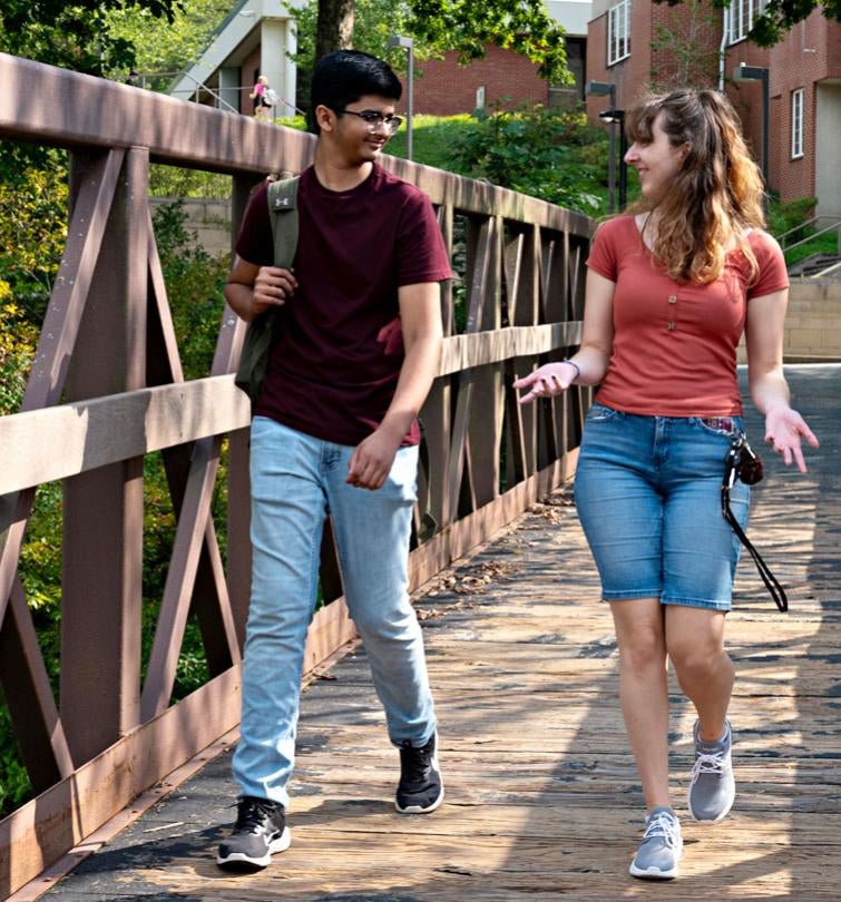 Two students have a conversation while walking across campus.