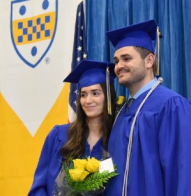 Two graduates posing for photo in regalia